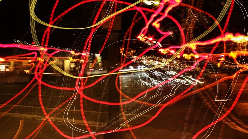 Red swirling light streaks on a dark city street background